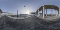 a 360 camera lens view of an outdoor area with a paved area and a blue sky