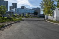 a paved area with trees in the middle of it and buildings in the distance along the road