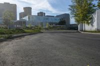 a paved area with trees in the middle of it and buildings in the distance along the road