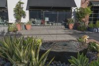 a stone water feature in the foreground outside a cafe and restaurant sign and awning