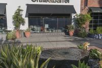 a stone water feature in the foreground outside a cafe and restaurant sign and awning