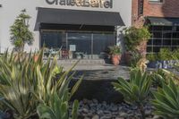 a stone water feature in the foreground outside a cafe and restaurant sign and awning