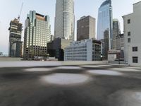 an empty parking lot in the middle of city buildings and a bench with a back wall
