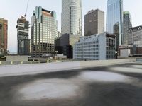 an empty parking lot in the middle of city buildings and a bench with a back wall