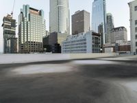 an empty parking lot in the middle of city buildings and a bench with a back wall