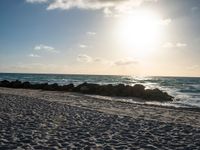 the sun rising over the beach on a sunny day with a small amount of sand