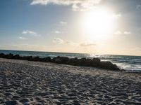 the sun rising over the beach on a sunny day with a small amount of sand