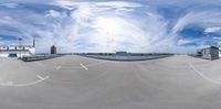 360 - angle lens photo taken of a skateboard park with blue skies, clouds and buildings