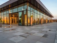 a building with a large glass building entrance and a lot of potted plants on the outside