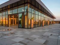 a building with a large glass building entrance and a lot of potted plants on the outside