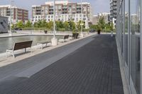 the street has two empty benches along side of it and apartment buildings in the background