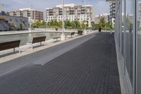 the street has two empty benches along side of it and apartment buildings in the background