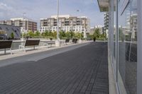 the street has two empty benches along side of it and apartment buildings in the background