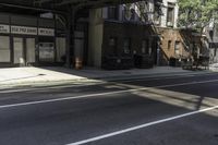 the empty sidewalk has a bus stop at it's side and the shadows come on the pavement