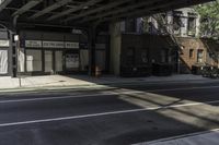 the empty sidewalk has a bus stop at it's side and the shadows come on the pavement