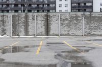 the empty parking lot has only snow on the ground in front of an old brick factory