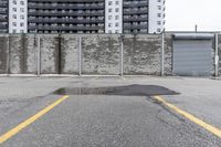 the empty parking lot has only snow on the ground in front of an old brick factory