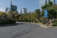 a roadway with lots of greenery in the background near skyscrapers and other buildings