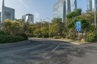 a roadway with lots of greenery in the background near skyscrapers and other buildings