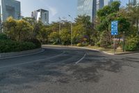 a roadway with lots of greenery in the background near skyscrapers and other buildings