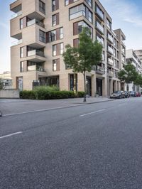 a street with a tree lined roadway, buildings and cars on it in the middle of a residential area