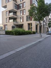 a street with a tree lined roadway, buildings and cars on it in the middle of a residential area