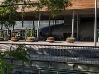 a bench sitting on top of a walkway under a building next to water and trees