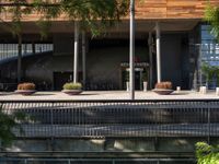 a bench sitting on top of a walkway under a building next to water and trees