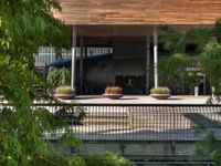 a bench sitting on top of a walkway under a building next to water and trees