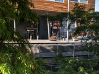 a bench sitting on top of a walkway under a building next to water and trees