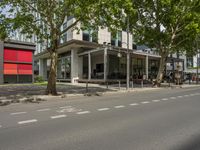 a big building sitting next to a tree and road next to it with some people