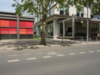 a big building sitting next to a tree and road next to it with some people