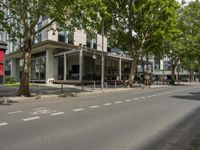 a big building sitting next to a tree and road next to it with some people