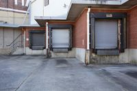 two closed garage doors on a sidewalk in an old industrial building with brick and plasterwork