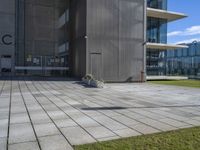 a grey building next to a sidewalk and grass with a black fire hydrant outside