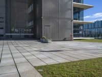 a grey building next to a sidewalk and grass with a black fire hydrant outside