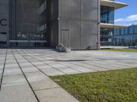 a grey building next to a sidewalk and grass with a black fire hydrant outside