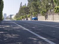 the trees on either side of the road have long shadows over it with an area for cars to drive by