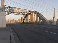 a bridge that is over a highway with buildings and a sky line in the background