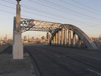 a bridge that is over a highway with buildings and a sky line in the background