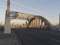 a bridge that is over a highway with buildings and a sky line in the background