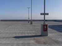 the empty parking lot of an airport with lots of vehicles parked nearby and one sign indicating an important area