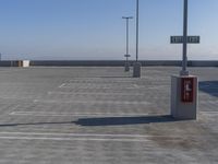 the empty parking lot of an airport with lots of vehicles parked nearby and one sign indicating an important area