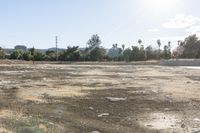 a field full of rubble and debris with buildings in the back ground behind it in the background