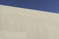 a white building that has been painted with grey paint and has a large area of dirt