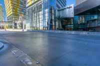 a man walks in a wide open urban area in the sunlight - like setting with modern glass buildings