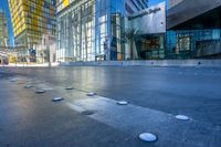 a man walks in a wide open urban area in the sunlight - like setting with modern glass buildings