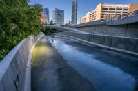 a picture of some tall buildings and water on the road in a city parkland