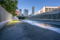 a picture of some tall buildings and water on the road in a city parkland