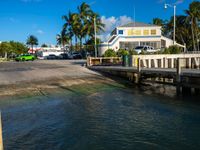 a view of the water from a dock with cars driving on it in front of a building